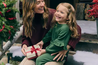 Girl and mother sitting with present on snow covered stairs