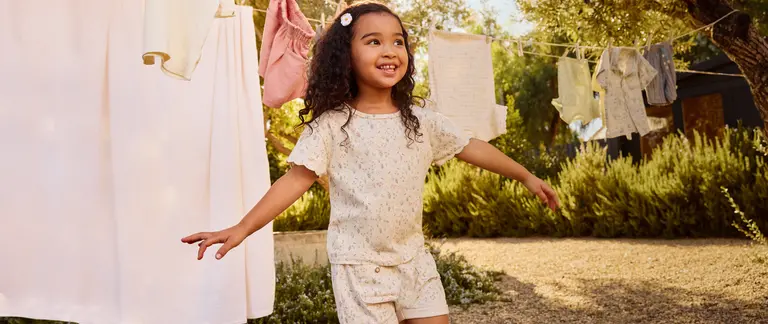 Girl playing in a backyard where clothes hang to dry.